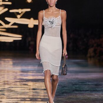 Model in a cream dress carrying a black handbag on the Chanel Spring–Summer 2027 runway