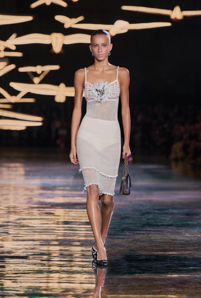 Model in a cream dress carrying a black handbag on the Chanel Spring–Summer 2027 runway